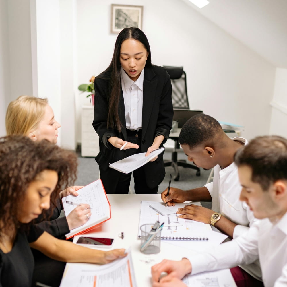 Recruitment manager leading a staffing or employee training session with a diverse team in a professional office meeting environment.
