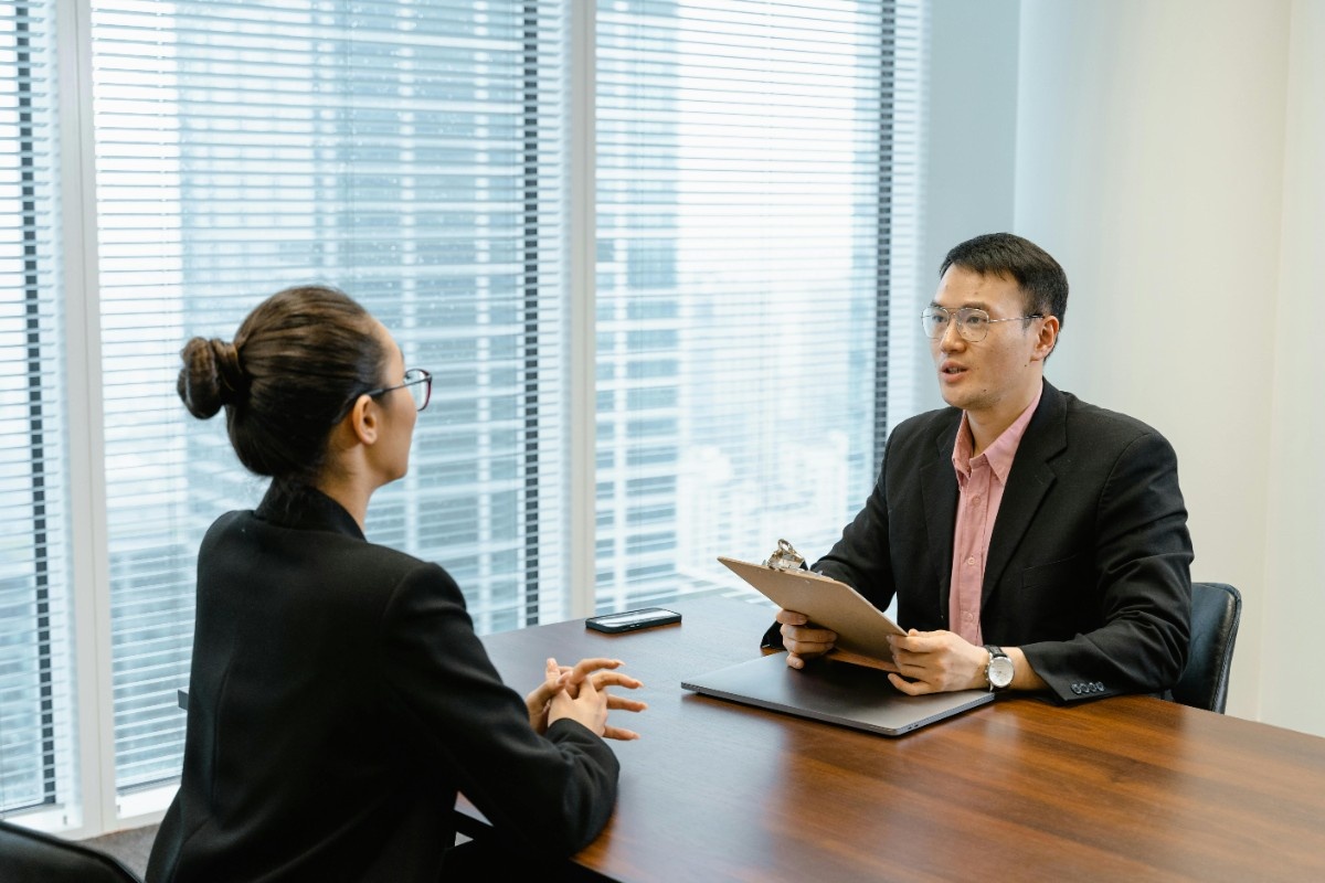 Recruitment professional interviewing a job candidate during a staffing and hiring consultation in a modern corporate office setting.